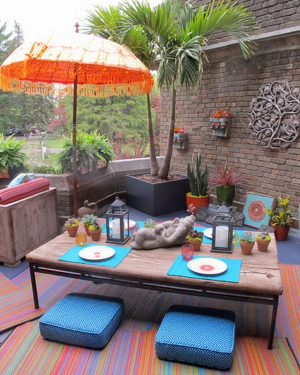 veranda party im sommer mit indischem flair statuetten und sonnenschirm in orange