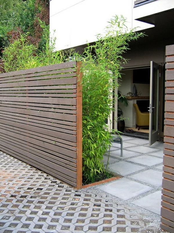 Gartenzaungestaltung den Außenbereich gestalten Gartensichtschutz aus Holzbalken und grünen Pflanzen