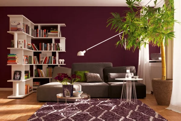Beerenfarben im Wohnzimmer warme Ausstrahlung im modern eingerichteten Raum Teppich Sofa Bücherregal 