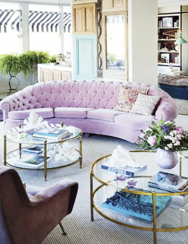 schick eingerichtetes Wohnzimmer bequemes rosa Sofa zwei Couchtische rund aus Glas mit Metallbeinen 