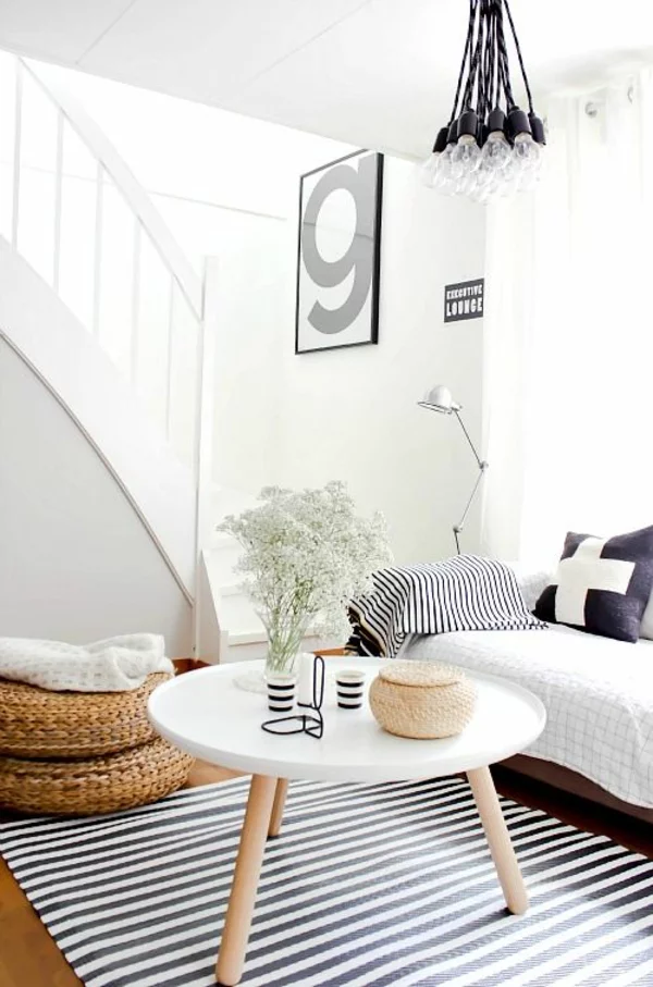 Couchtisch rund hmit Tischbeinen aus Holz im modern gestalteten Wohnzimmer in weiß schwarz