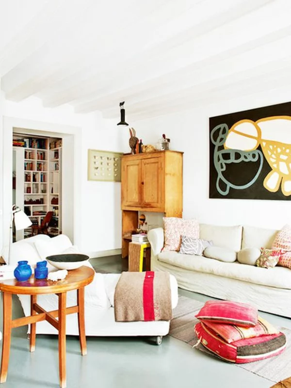 gemütlich eingerichtetes Wohnzimmer Wanddeko Sofa Holzschrank runder Couchtisch 