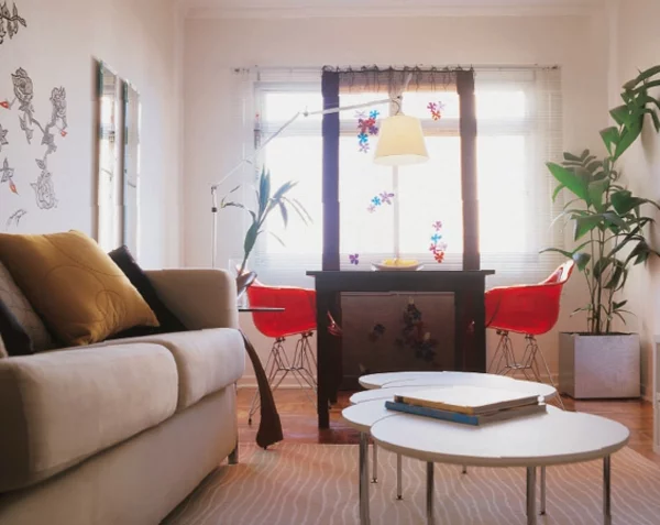 modernes Wohnzimmer gestalten mit drei runden Couchtischen Polstersofa Essecke Bogenlampe Topfpflanze in der Ecke 