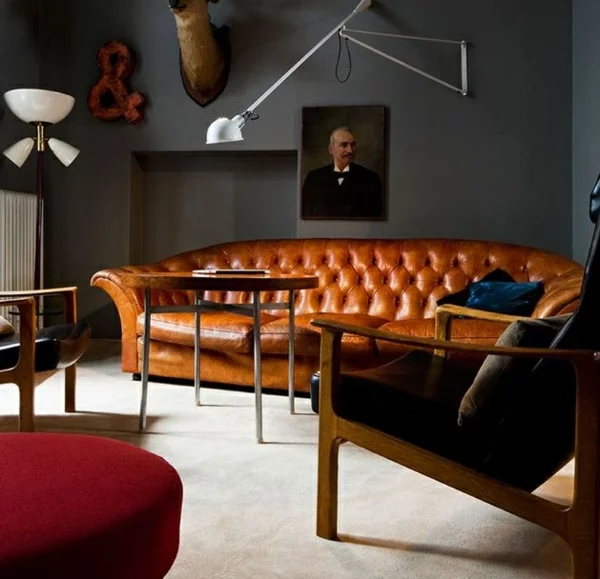 dunkelgraue Wandfarbe im Wohnzimmer klassische Einrichtung Ledersofa in einer warmen Braunnuance 