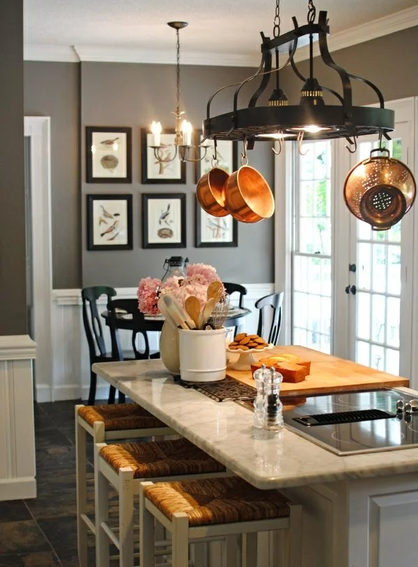 graue Wandfarbe in Küche und Esszimmer schöne Bilder an der Wand Esstisch mit Hockern hängende Pfannen und Töpfe 