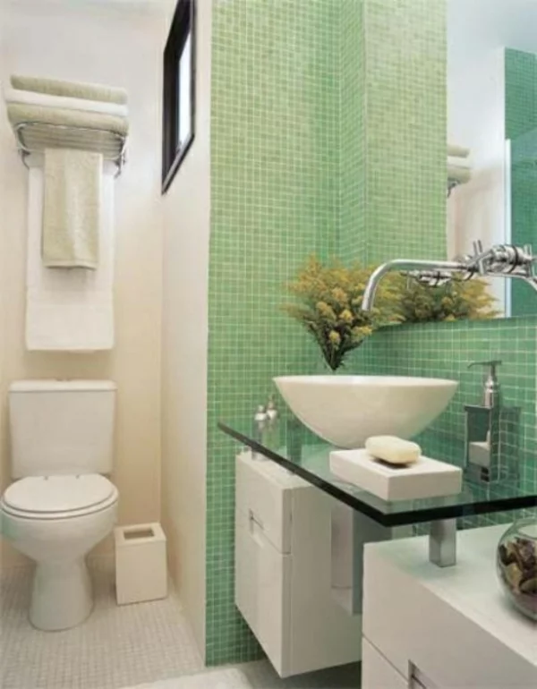 kleines Bad einrichten Wandgestaltung grüne Fliesen Waschtisch mit Glasplatte weiße Badmöbel WC gelb-grüne Blumen 