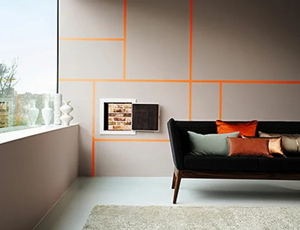 Wandfarbe grau im Wohnzimmer geometrische Muster mit orangenfarbenen Streifen und ein Stück freigelegte Ziegelwand 