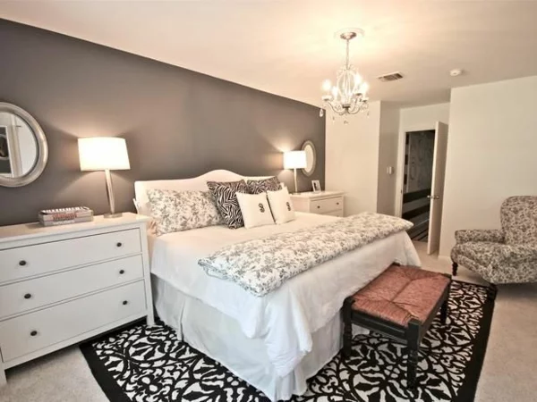 harmonisch gestaltetes Schlafzimmer Wandfarbe grau großes Schlafbett weiße Bettwäsche 