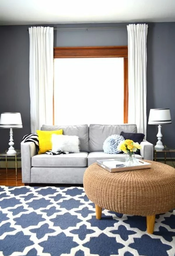 gemütliches Wohnzimmer gestalten Wandfarbe grau Rattanhocker kleines Sofa und weiße Gardinen