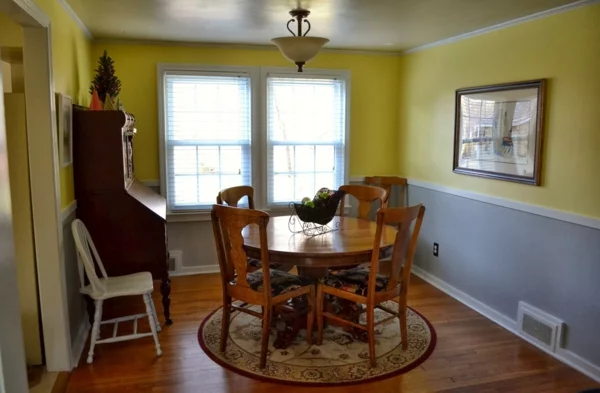 Esszimmer einrichten mit rundem Esstisch zwei Wandfarben grau und gelb 