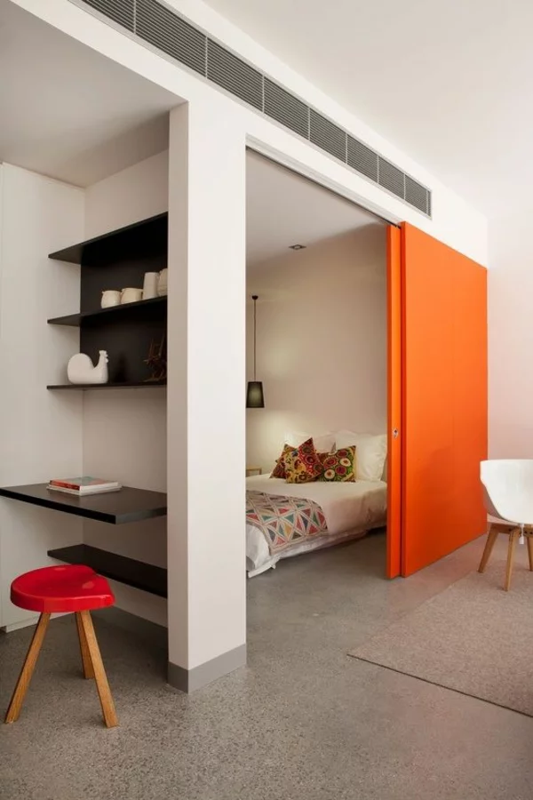 moderner Raumtrenner orangefarbene Schiebetüren zwischen Schlaf-und Wohnbereich 