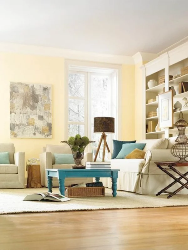 gemütliches Wohnzimmer Wandfarbe gelb Pastellfarben Couchtisch aus Holz in blau Regal Stehlampe 