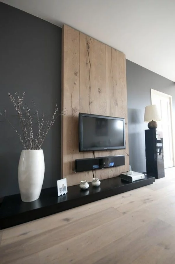 Wanddeko aus Holz im Wohnzimmer TV Wand mit Flachfernseher weiße Vase daneben und Holzboden unten 