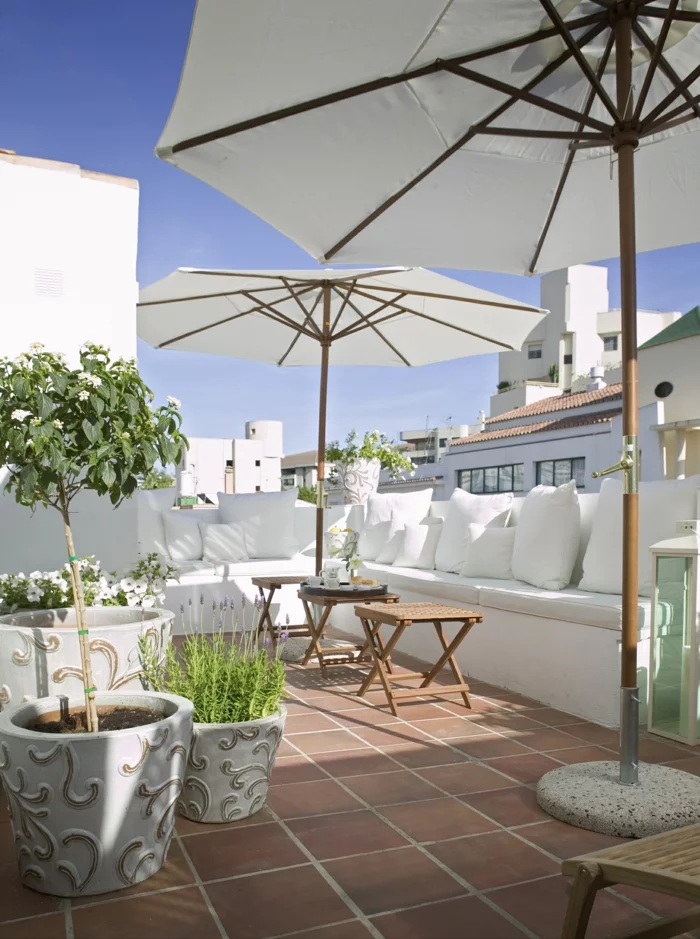 Terrasse neu gestalten mit weißen Balkonmöbeln, großen Kübelpflanzen und Sonnenschirmen