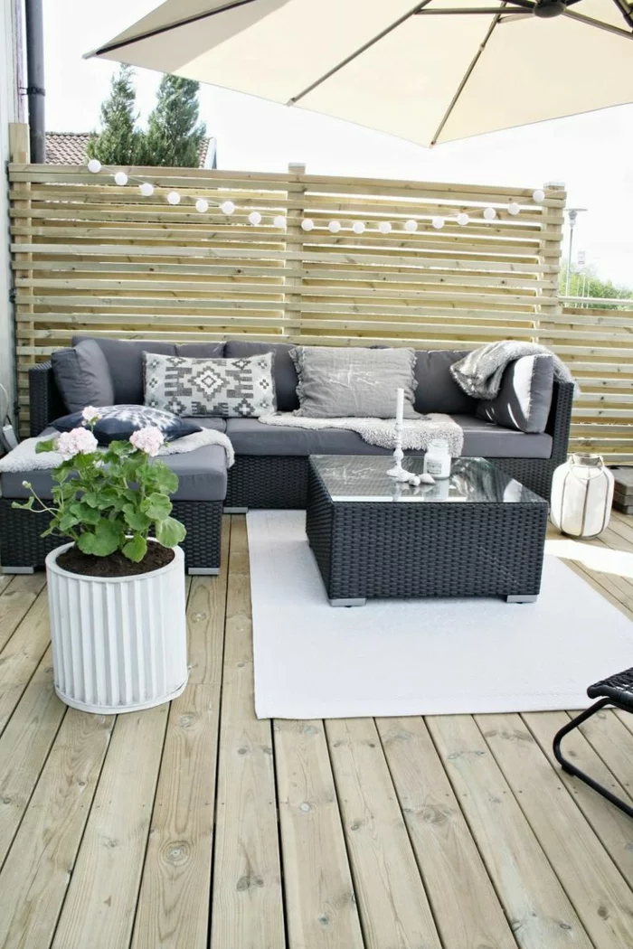 Terrassengestaltung für kleine Terrasse mit grauen Rattan Möbeln und weißem Teppich