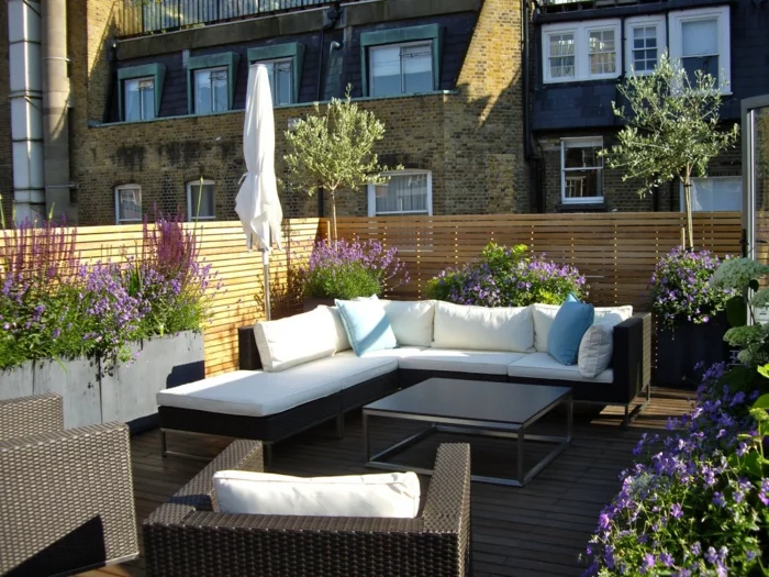Terrassengestaltung mit Außenmöbeln aus Rattan und weißen Gartenauflagen 