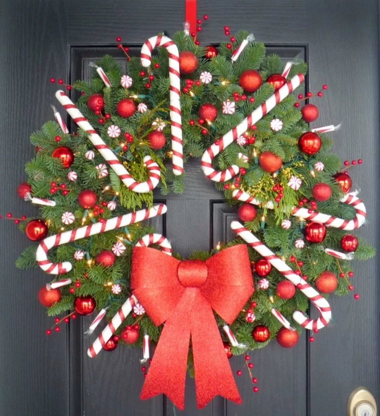Weihnachtskranz selber basteln an der Eingangstür rote Schleife Tannengrün Zuckerstangen