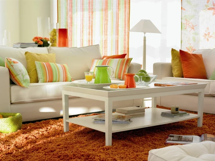 kleines wohnzimmer einrichten weißes sofa couchtisch orange hochflorteppich dekokissen