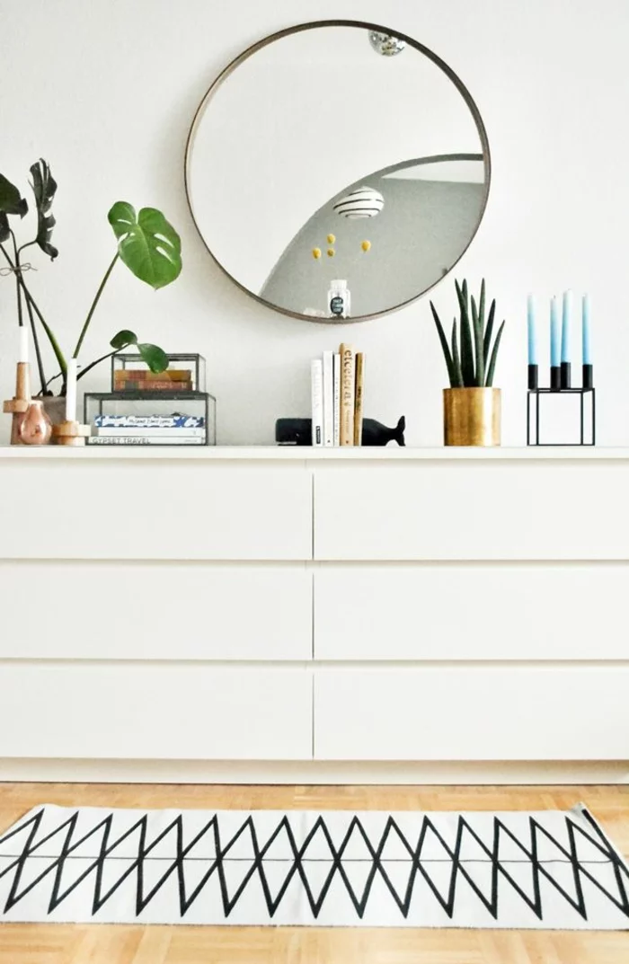 minimalistisches, weißes Sideboard dekorieren mit Monsterablättern, Büchern, Bogenhanf und Kerzenständer