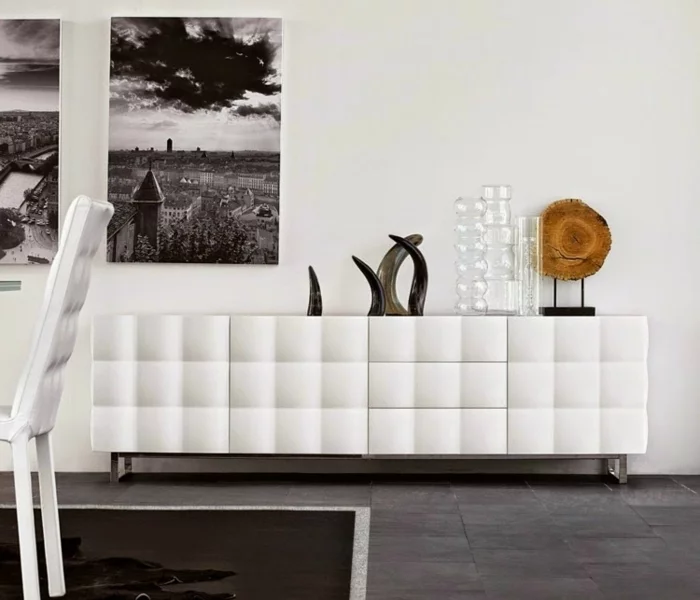 weiße Kommode dekoriert mit Glasvasen, Baumscheibe und abstrakter Deko 