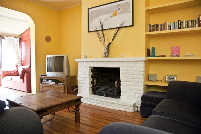 wohnzimmer streichen ideen gelbe wandfarbe kamin schwarze wohnzimmermöbel