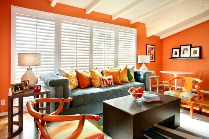 wohnzimmer streichen ideen orange wände dekokissen hellblaues sofa
