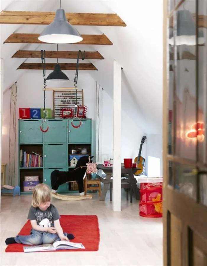 kleines Kinderzimmer mit Dachschrägen, Holzbalken und Wandregal in Blaugrün 