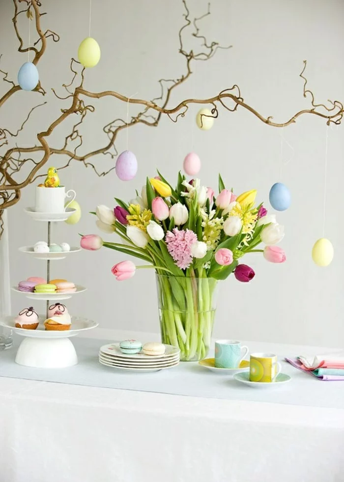 österliche Tischdeko mit bunten Eiern und Frühlingsblumen in der Vase