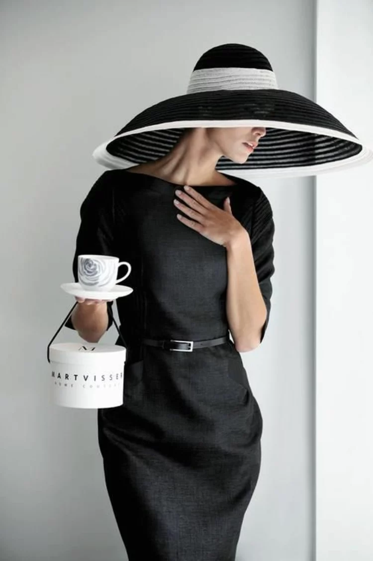 schwarz-weißer Hut mit breiter Krempe eleganter Look schwarzes Kleid mit Lederband 
