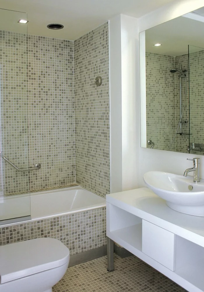 kleines Bad mit Mosaikfliesen und weißen Badmöbeln