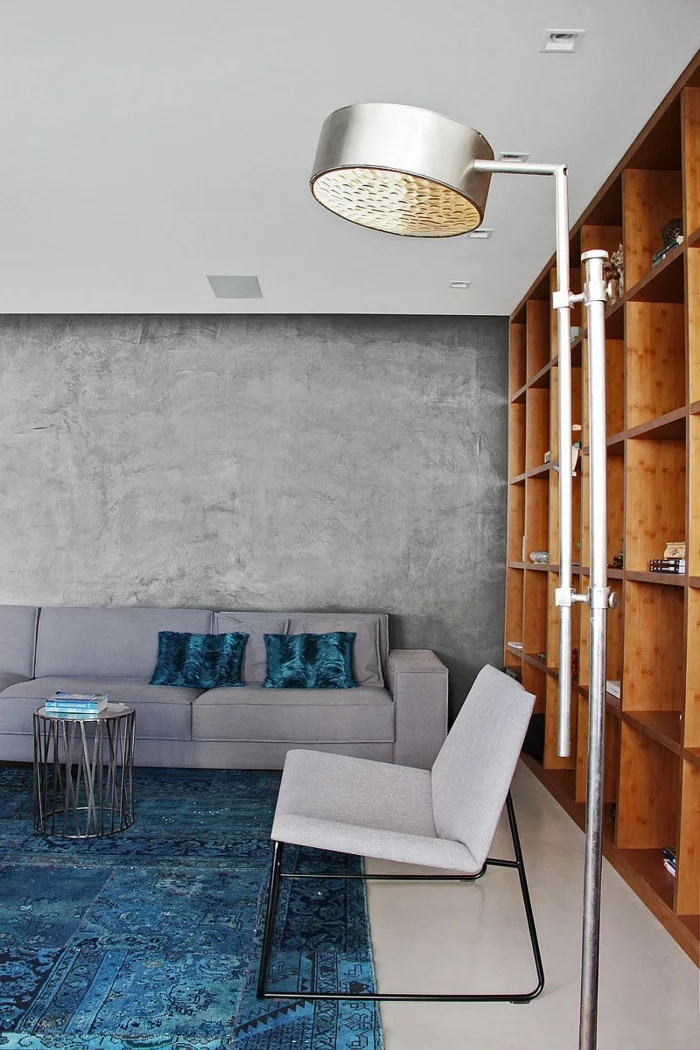 schöne wohnideen wohnzimmer einrichten betonwände blauer teppich regalsystem