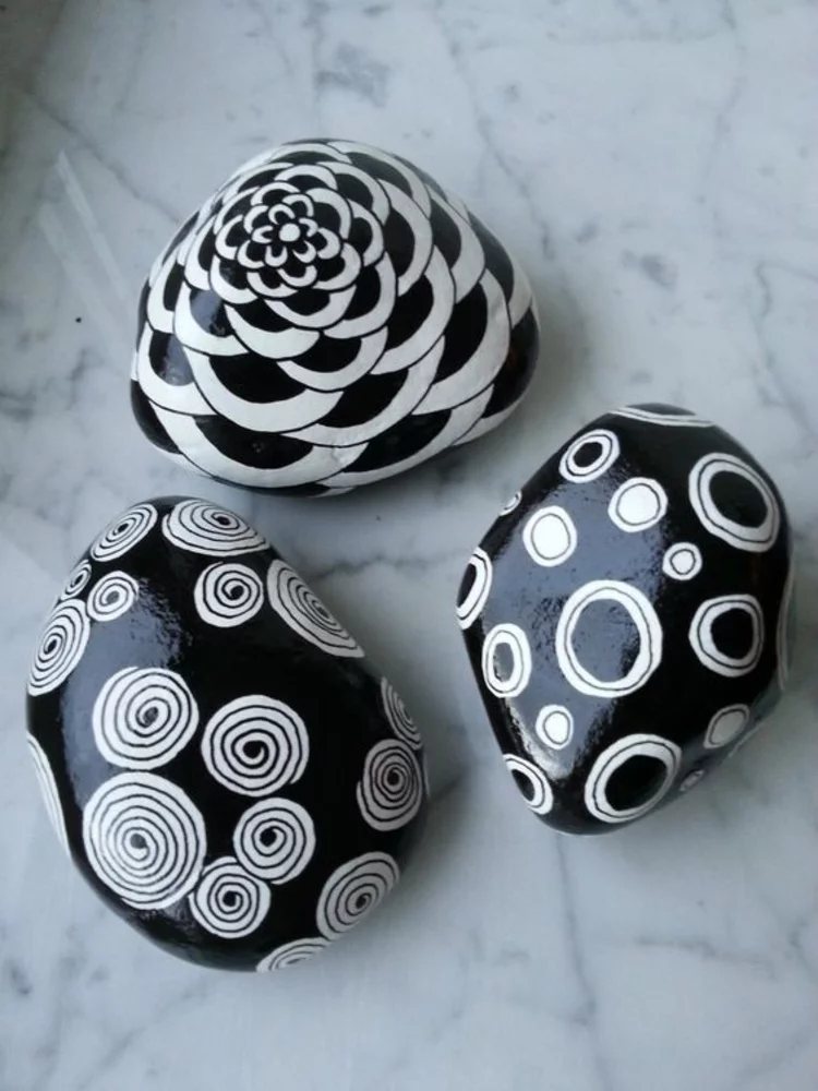 weiße Muster auf schwarzem Hintergrund Steine bemalen kreative Bastelideen mit Steinen