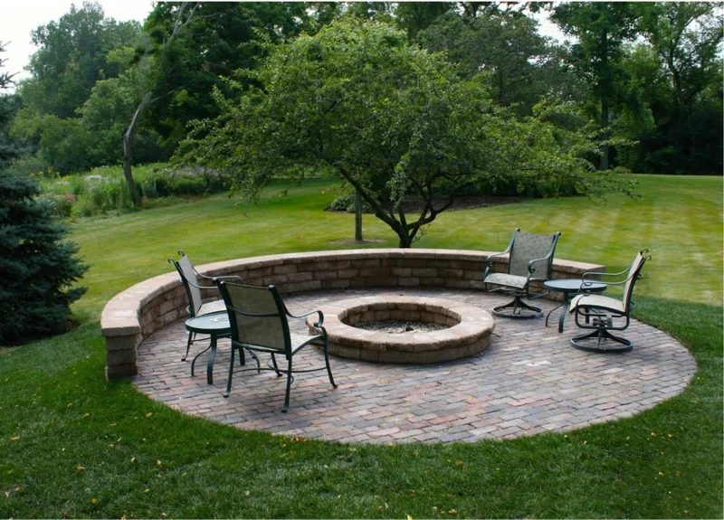 Feuerstelle bauen Gartengestaltung mit Steinen Kreis Stühle aus Metall grüner Rasen 