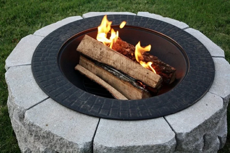 Feuerstelle bauen aus Stein runde Form brennendes Feuer 