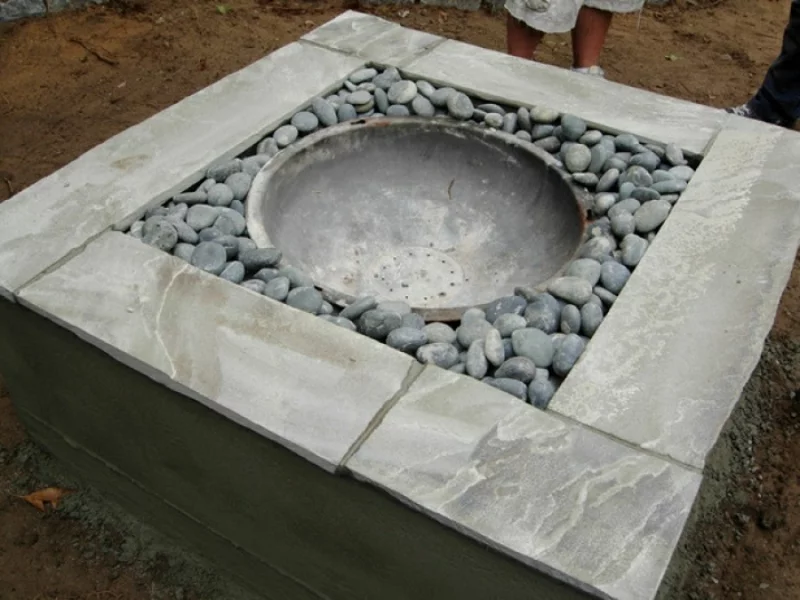 Feuerstelle bauen in runder Form aus Steinplatten und Flusssteinen Gartengestaltung