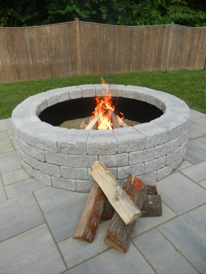 Feuerstelle bauen grauen Steinplatten Brennholz loderndes Feuer im Hinterhof 