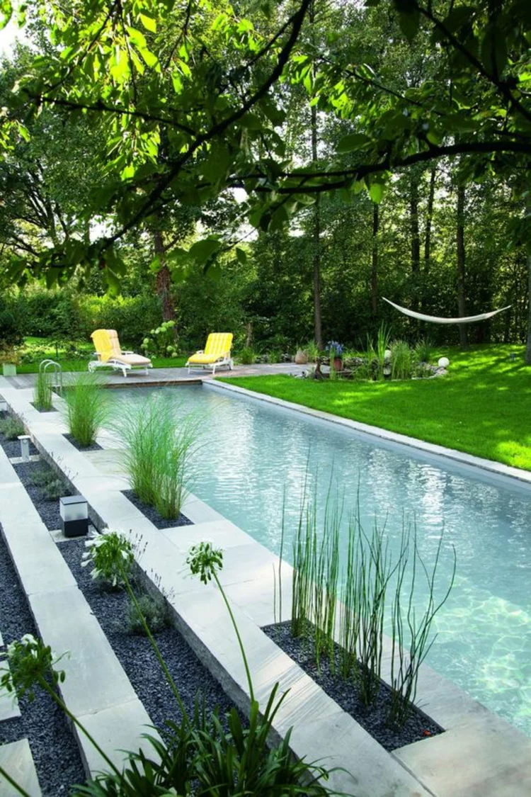rechteckiger Gartenteich moderne Gartengestaltung aus Beton Teich Gartenpflanzen  zwei Liegestühle 