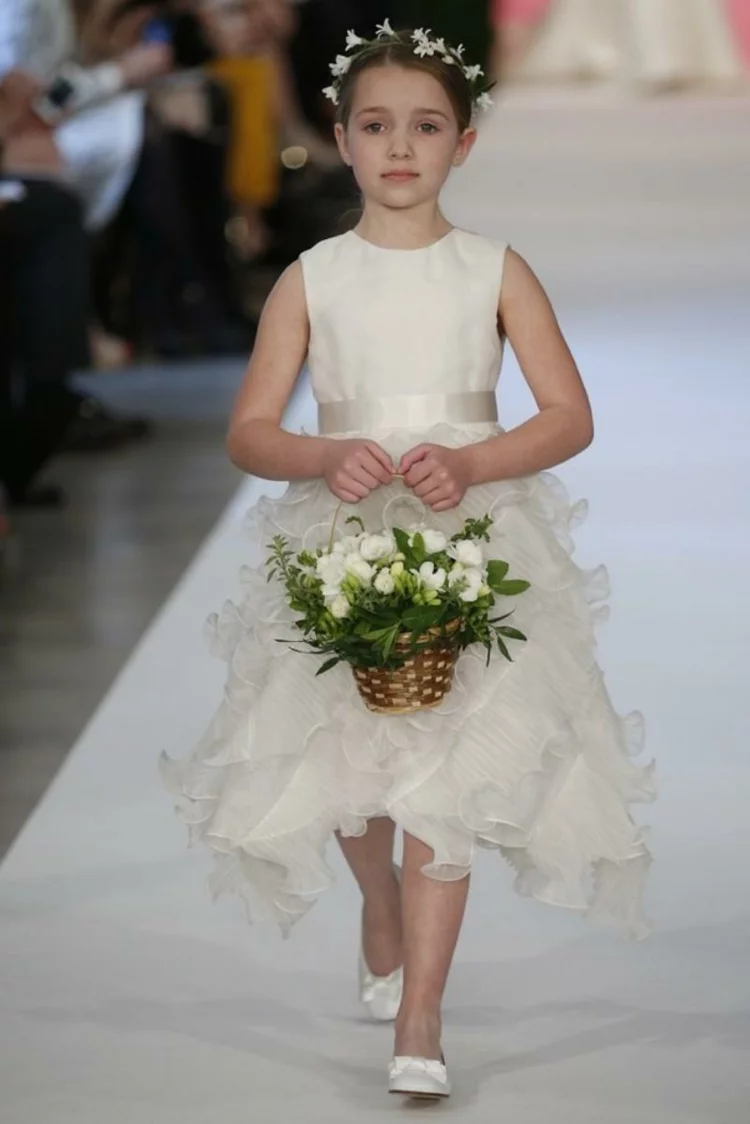 Kinderfrisuren für Mädchen Steckfrisuren für Kommunion Bild vom Laufsteg kleines Mädchen trägt weißes Kleid Haarkette und Korb mit weißen Blumen 