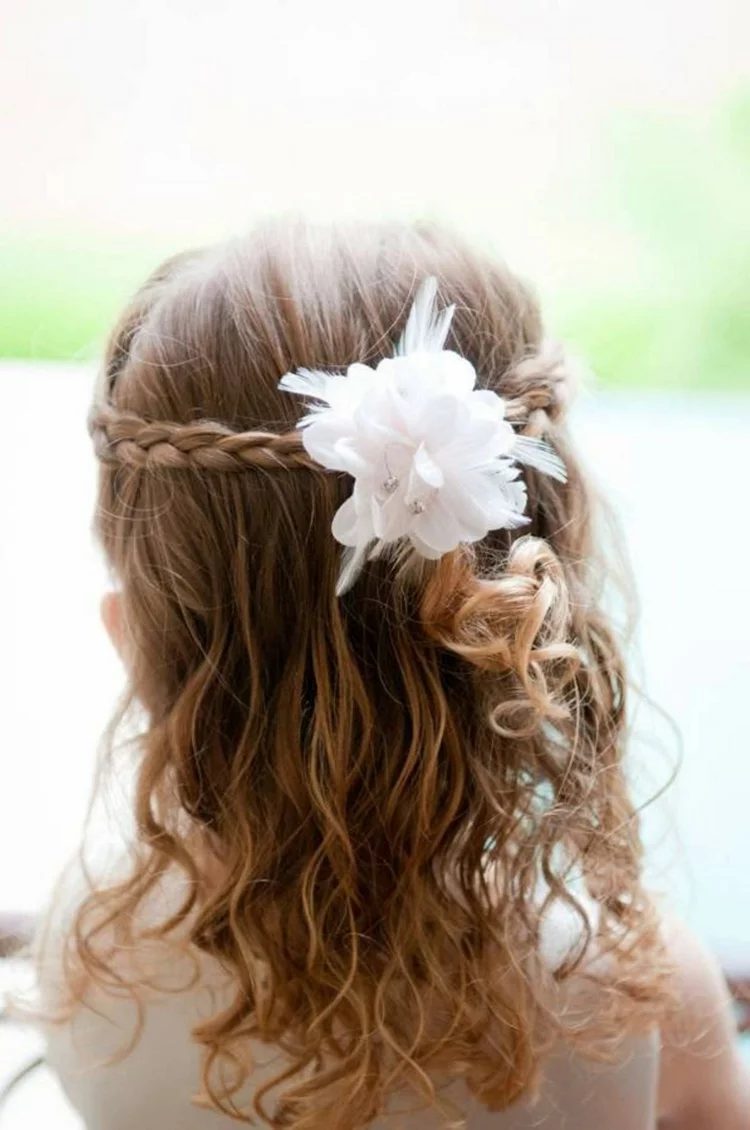 Kommunionfrisuren geflochtener Zopf und offen gelassenes Haar festliche Kinderfrisuren für Mädchen mit weißer Blume als Haarschmuck