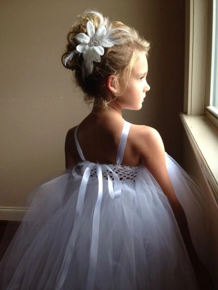 kleines Mädchen schick gekleidet weißes festliches Kleid Kommunionfrisuren mit Haaraccessoires weiße Blume im Haar