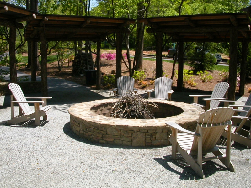 Stein Feuerstelle bauen Gartengestaltung mit Steinen Gartenstühle Holz
