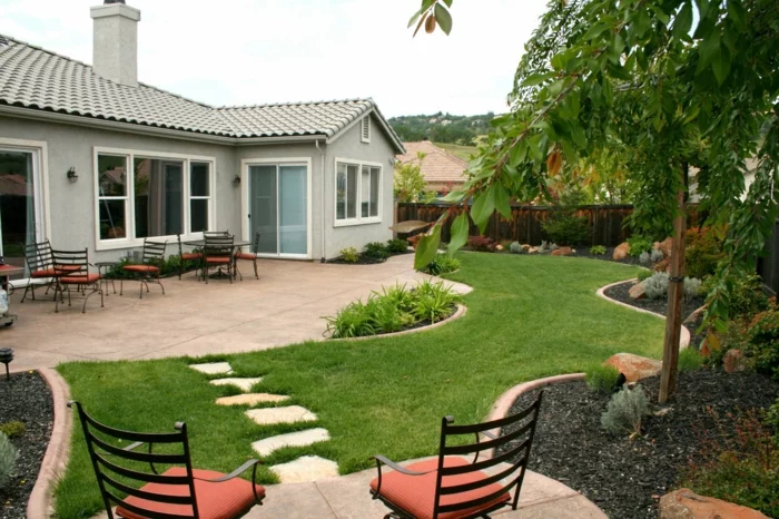geordneter Hinterhof mit grünem Rasen und Sitzecke mit Steinplatten