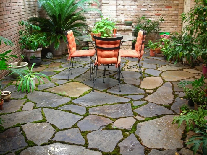 Gartengestaltung mit Steinplatten als Bodenbelag und Gartenmöbeln
