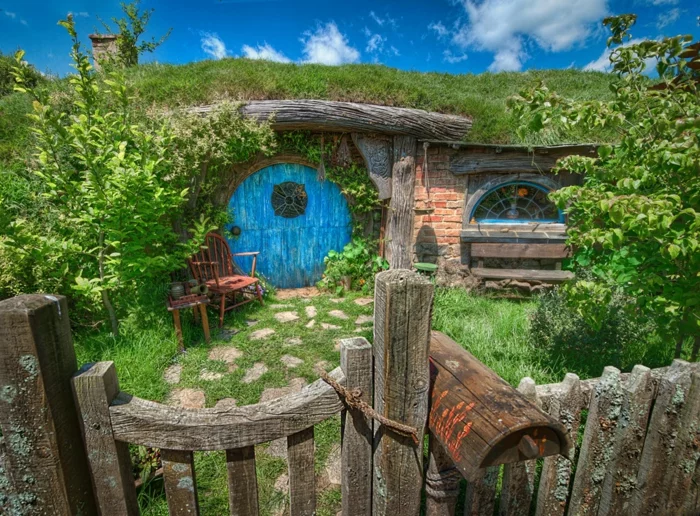 märchenhaftes DIY Hobbit Gartenhaus mit runder, blauer Tür und Gartenzaun 