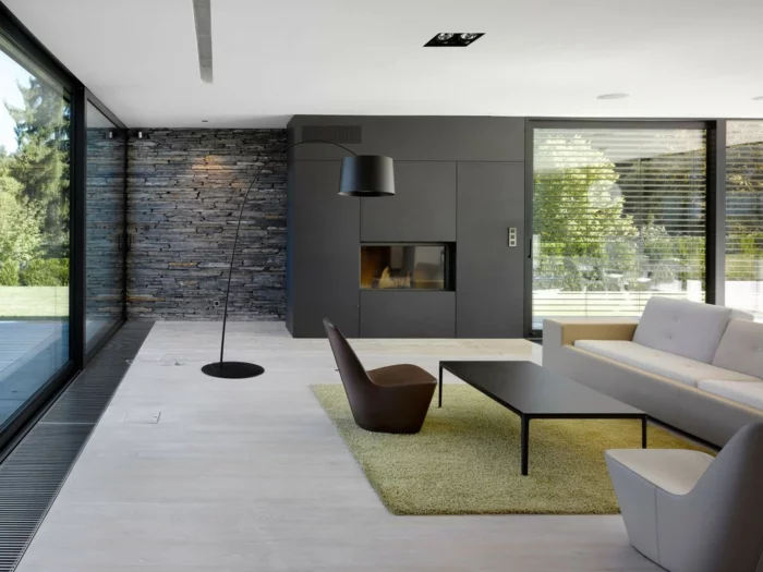 Wohnzimmer mit Steinwand in Grau, hellgrünem Teppich und hellem Boden