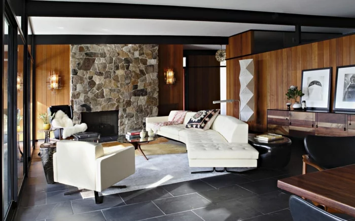 Wohnzimmer mit Steinwand, grauen Bodenfliesen, Retro Möbeln und hellem Teppich