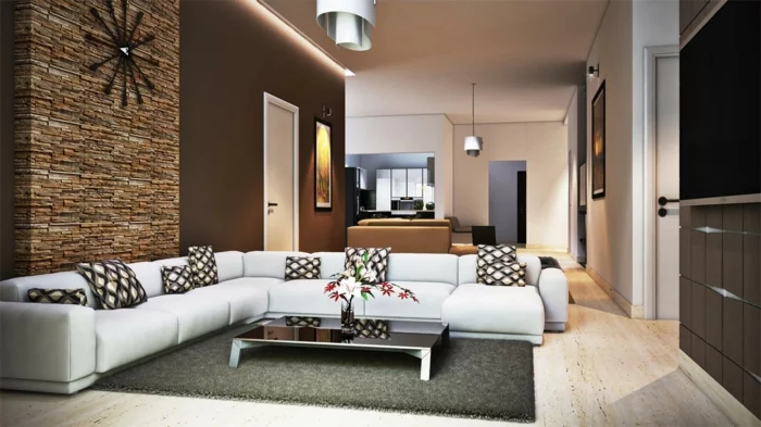 Wohnzimmer mit Steinwand, braunen Wänden, weißem Ecksofa und Glastisch