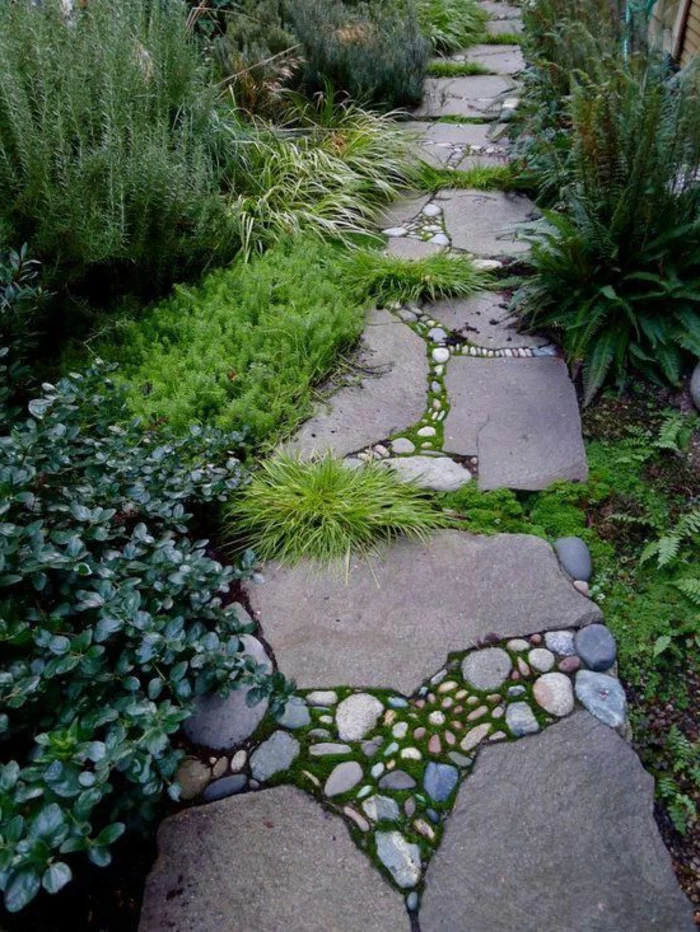 Gartenweg aus Steinplatten mit Kieselsteinen und Gras in den Fugen