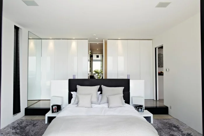 schlafzimmer weiß grauer teppich moderner kleiderschrank schwarzes bettkopfteil