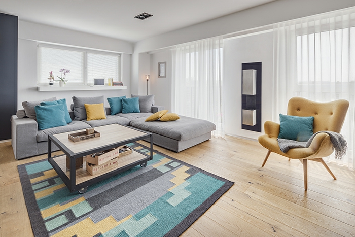 sofa grau farbige dekokissen bunter teppich gelber sessel